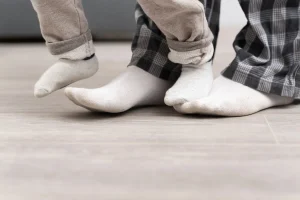 How long before you can walk on newly installed flooring. Person standing in socks on newly installed hardwood flooring, waiting before walking fully to protect the surface.
