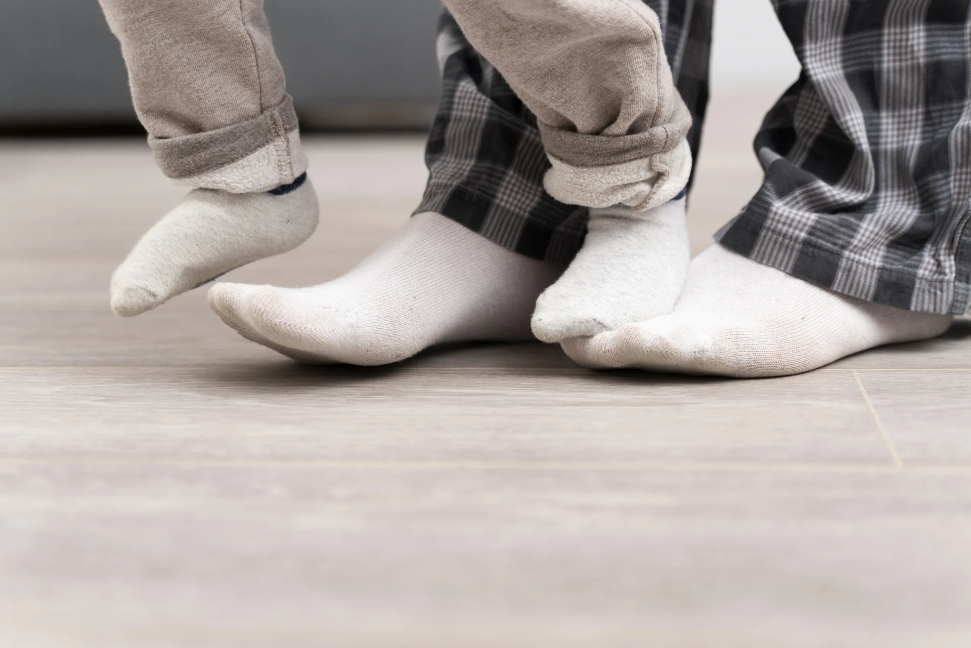 How long before you can walk on newly installed flooring. Person standing in socks on newly installed hardwood flooring, waiting before walking fully to protect the surface.