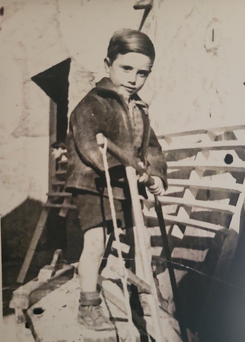 James Mazzamuto as a young boy in Sicily, standing on a workbench and working a frame saw